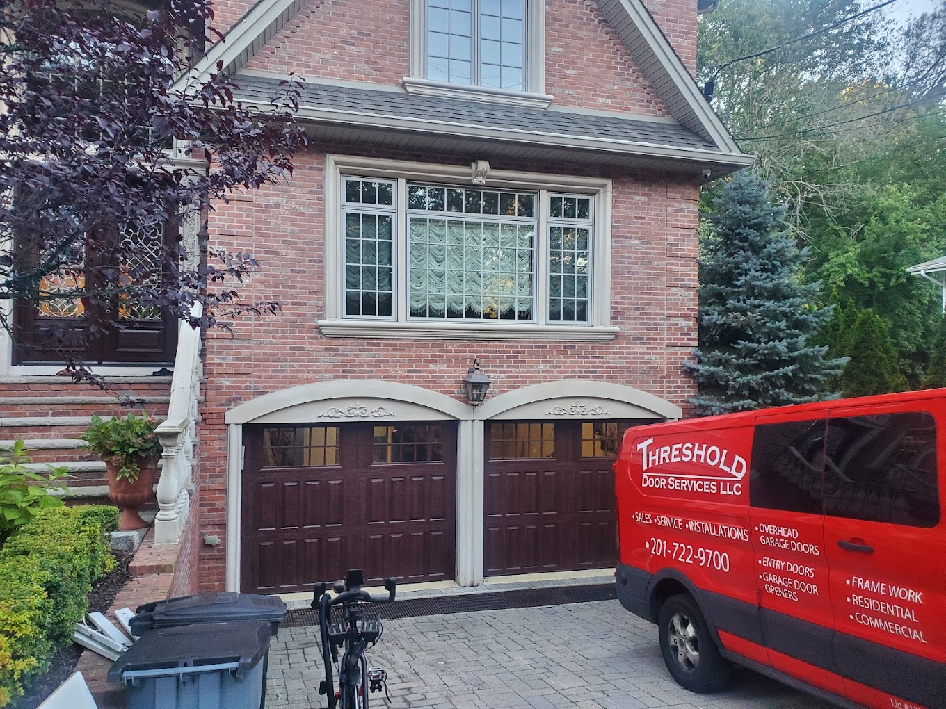 Threshold Door Services, LLC truck in from on garage door on brick house